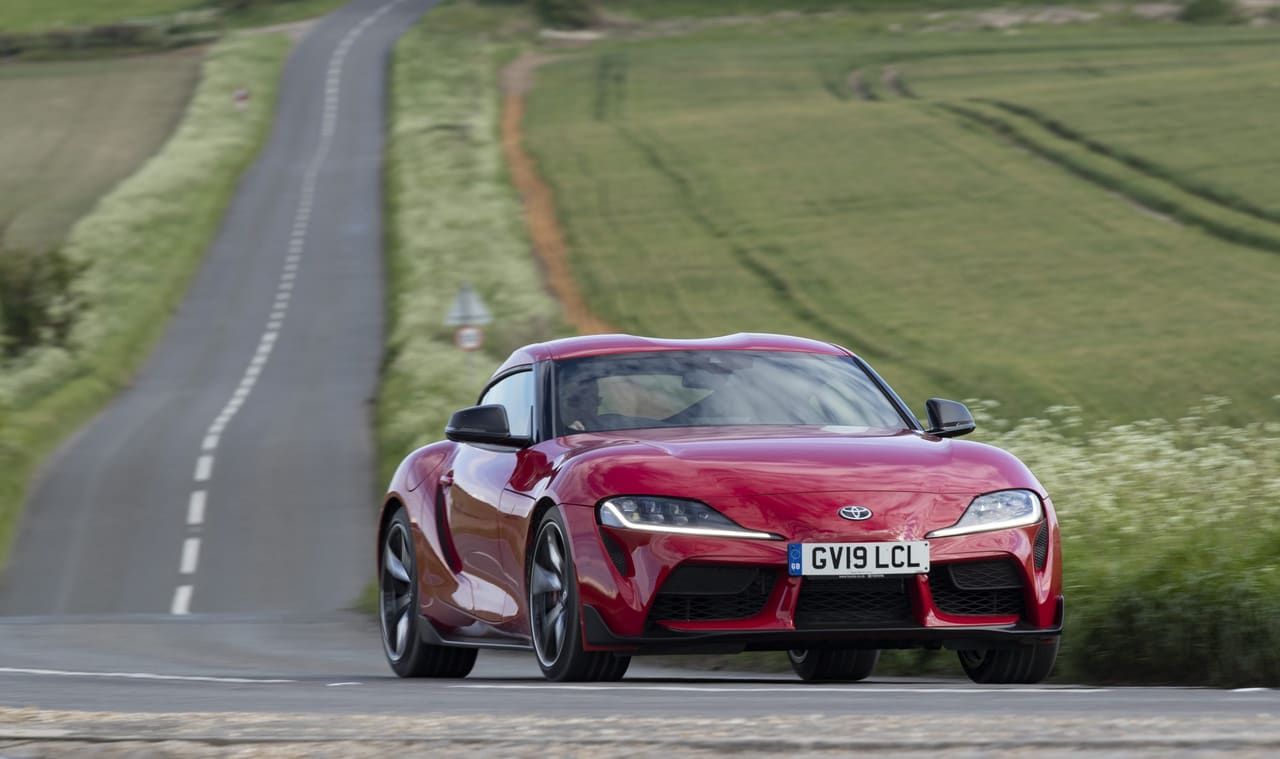 A red Toyota GR Supra on a country road in the UK